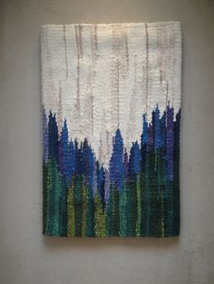 a painting hanging on the side of a wall next to a white wall with blue and green trees