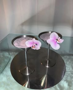 two silver trays with pink flowers on them sitting on a white furnishing