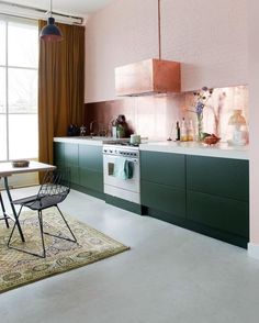 a kitchen with pink walls and green cabinets in the center, along with a rug on the floor