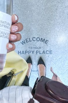 a woman is holding a cup with her feet on the ground next to some shoes