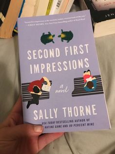 a person holding up a book in their hand with the title second first impressions on it