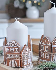 two gingerbread houses are sitting on a tray with some candles in front of them