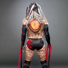 the back of a man's body with tattoos on it and an eye painted on his chest