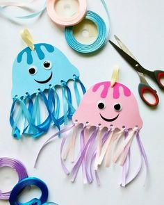 two jellyfishs are sitting next to each other on a table with scissors and thread