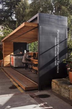 a man sitting at a table in front of a black box on top of a wooden platform