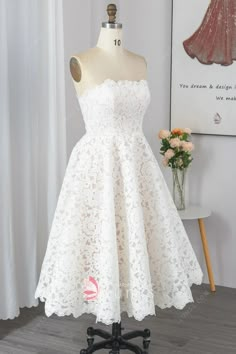 a short white lace dress on a mannequin stand in front of a window