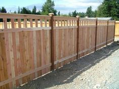 a wooden fence that is next to a gravel road