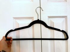 a person holding a black hanger in front of a door