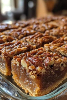 a close up of a pie with pecans on top in a glass dish, ready to be eaten