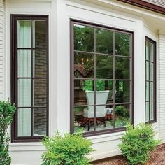 an open window on the side of a house with potted plants in front of it