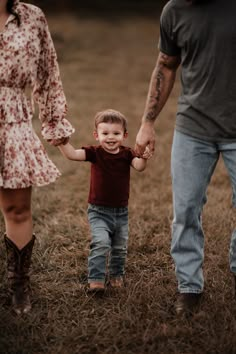 a little boy holding the hand of his mom and dad