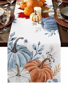 the table is set with pumpkins and other autumn decorations