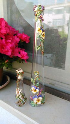 two vases with flowers in them sitting on a window sill next to a potted plant