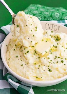 a bowl filled with mashed potatoes on top of a green and white checkered table cloth