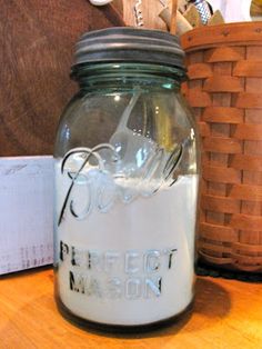 a glass jar sitting on top of a wooden table next to a basket and scissors