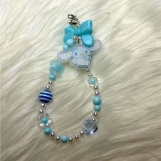 a blue and white beaded necklace with a hello kitty charm on it's end