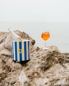 a glass of wine sitting on top of a rock next to a bucket and bottle