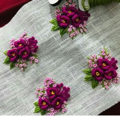 some purple flowers are sitting on a white table cloth next to thread and spools