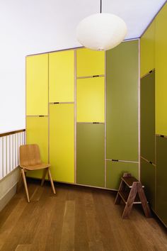 a room with yellow and green walls, wooden flooring and a chair in the corner