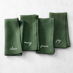 four green napkins with embroidered words on them