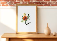 an orange flower is displayed in a wooden frame next to a vase and brick wall