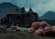 pumpkins and other decorations sit on the ground in front of an old stone house