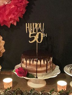 a birthday cake sitting on top of a table next to cupcakes and candles