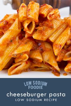 cheeseburger pasta with tomato sauce on a white plate in front of a wooden bowl