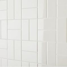 a white tiled wall with black grouting on it