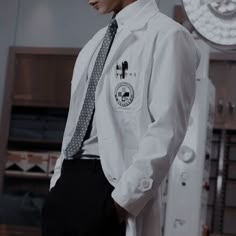 a man wearing a white lab coat and tie standing in front of a machine room