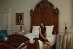 a woman sitting on top of a bed next to a wooden headboard and foot board