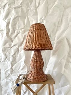 a wicker lamp sitting on top of a wooden table next to a white wall