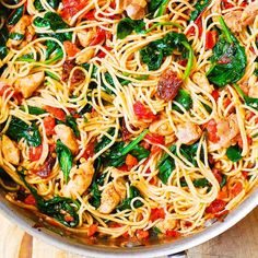 a skillet filled with pasta, chicken and spinach