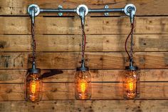 three mason jar lights are hanging on a wooden wall