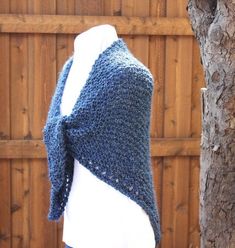 a knitted shawl draped over a white mannequin's torso in front of a wooden fence