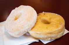 two donuts sitting on top of a white napkin