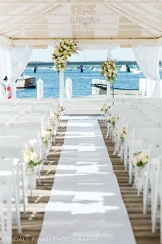 the aisle is lined with white chairs and flowers