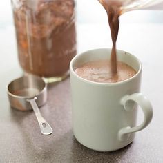 a person pouring chocolate into a white cup