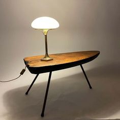 a wooden table with a lamp on it and a cord attached to the end that is plugged in