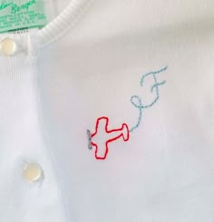 a white shirt with red and blue stitching on it