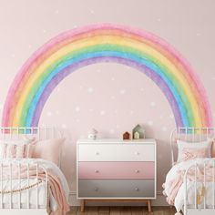 a bedroom with two beds and a rainbow painted on the wall