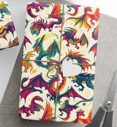 the wrapping paper has colorful dragon designs on it and is tied to a pair of scissors