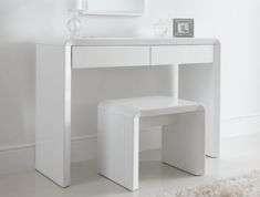 a white vanity table with two stools and a mirror on the wall above it