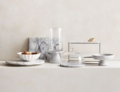 marble plates and bowls are arranged on a white countertop, with one bowl in the middle