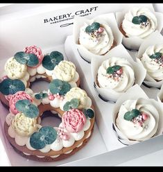 a box filled with cupcakes covered in frosting and flower decorations on top of each other