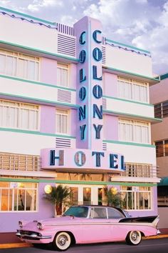 an old pink car parked in front of a tall building with the word colony hotel on it's side