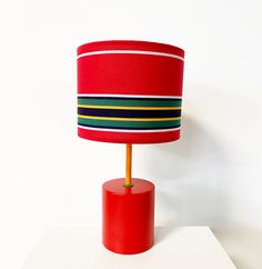 a red table lamp sitting on top of a white surface