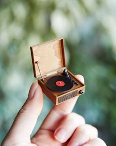 a hand holding a small wooden record player