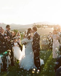 a bride and groom are surrounded by bubbles as they walk down the aisle