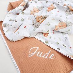 an orange and white blanket on top of a table with the name aude printed on it